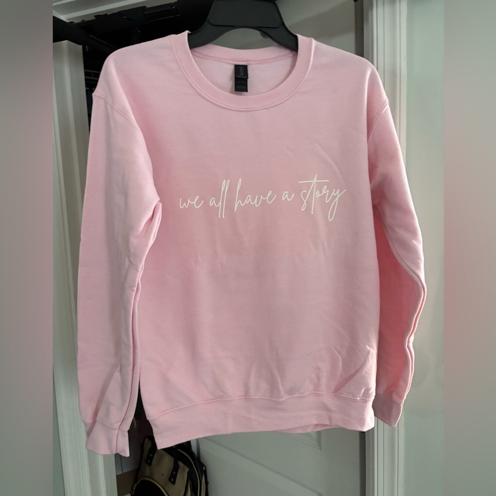 NWT “we all have a story” bright pink sweatshirt with white writing